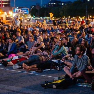 Audience sitting on Bristol harbourisde watching an out door film screening as part of Watershed's Cinema Rediscovered