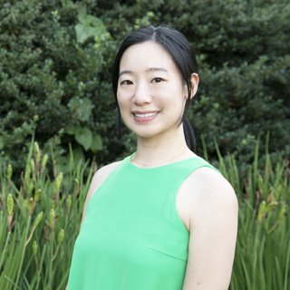 A woman in a green, sleeveless top smiles at the camera.
