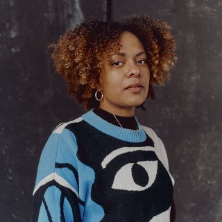 Photo of a black woman wearing a blue, black and white jumper