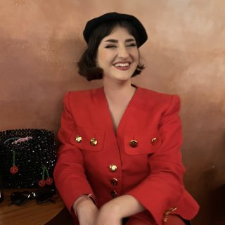 Portrait of Isla Williams in her early 30s wearing a bright red jacket and black beret