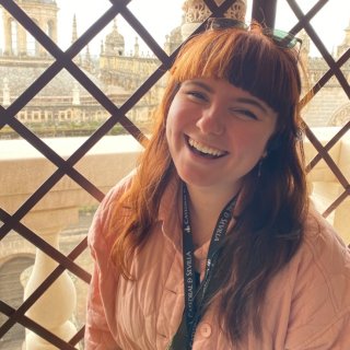 Portrait of a white woman in her 20s laughing whilst looking at the camera