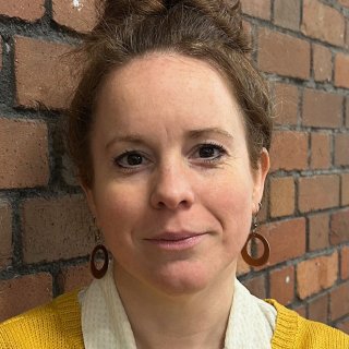 Close up portrait photo of a woman standing against a wall 