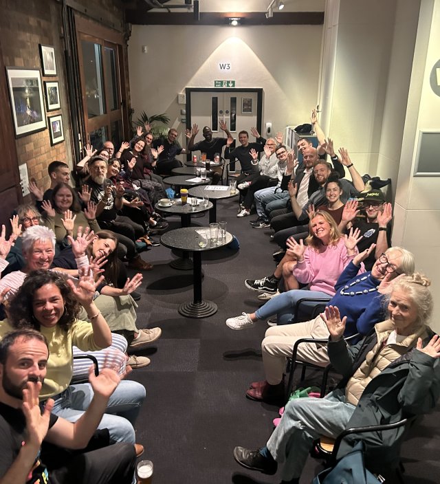 A large group of people with raised hands in the air in greeting