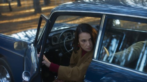 Film still from 1976 of Aline Küppenheim looking at something from her car.