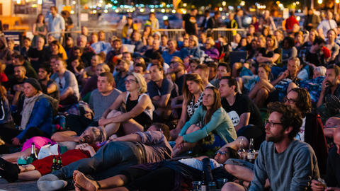 Photo of people sat on the ground watching g a cinema screening in Bristol harbourside