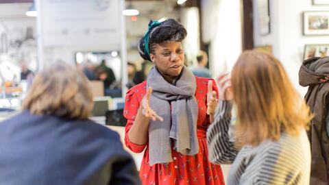 Photo of a woman standing and chatting to two other people