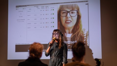 Photo of Victoria Melody holding a mic talking to an audience.