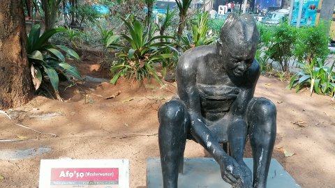 Statue of a woman washing clothes in a bowl