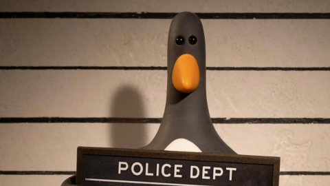 An stop-motion penguin holds a police sign, indicating he has been arrested.