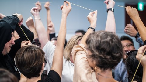 Photo of a group of artists holding twine together