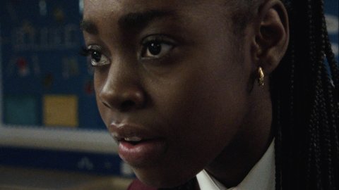 A girl in school uniform stares off into the distance.