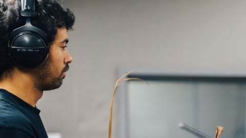 A young person in a music studio with headphones on.