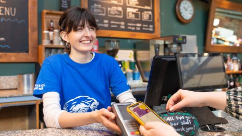An image of a person taking payment from a customer at the bar