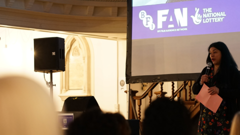 A picture of Lorena Pino speaking into a microphone on International Women’s Day 2025.