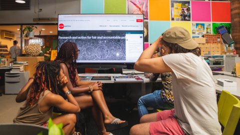 Three people sitting around a monitor looking at the screen.