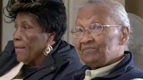 Two older black women, one looking into the camera