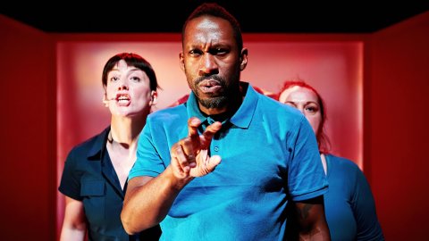 Three people, on stage, facing front and using British Sign Language