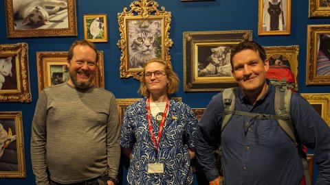 Three smiling people who are from Airgiants smile into the camera with cats behind them.