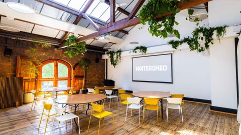 Spacious, bright airy event space with sanded floorboards, high ceiling, loft beams and leafy foliage