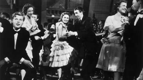 A man and woman dance holding hands at a festive party