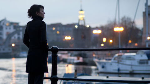 Woman standing on a quayside at sunset.