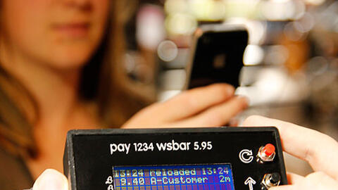 Woman using a phone to make a £B payment at Watershed Bar