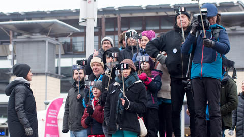 Group of people holding phones up with selfie sticks