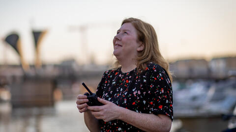 Woman holding a walkie talkie looking up at the sky