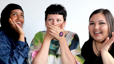 Three women with one covering her mouth with her hands