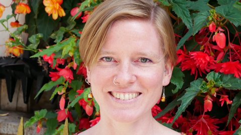 Headshot of Kate Arthurs, Watershed Board member, wearing a brown, patterned top with flowers in the background