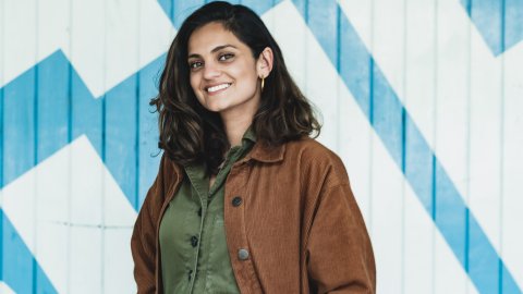 Photo of Nida Manzoor standing in front of a large Watershed logo.