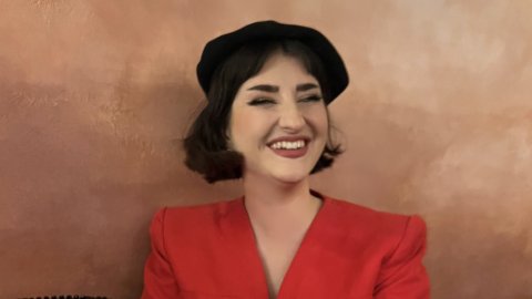 Portrait of Isla Williams in her early 30s wearing a bright red jacket and black beret
