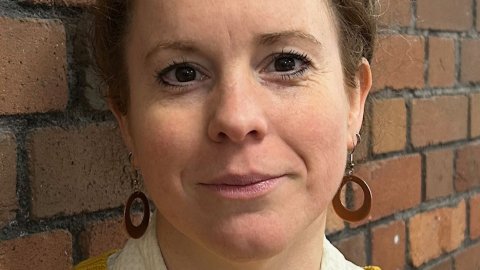 Close up portrait photo of a woman standing against a wall