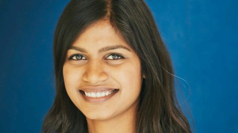 Head shot of a smiling woman on a blue background.