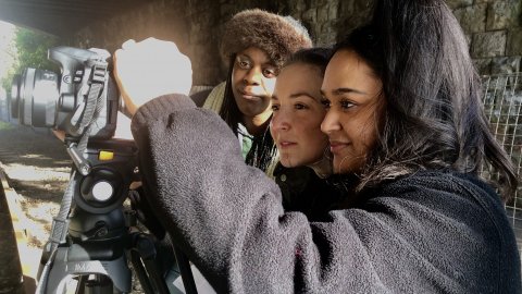 Image of three young filmmakers using camera equipment