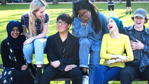 Group of young people on a bench laughing