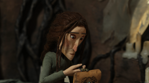 A character with brown hair in a green outfit holds a small wooden box, surrounded by a dark, textured background.