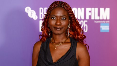Photo of a woman with red braided hair and a black dress at a film festival against a purple and pink backdrop.