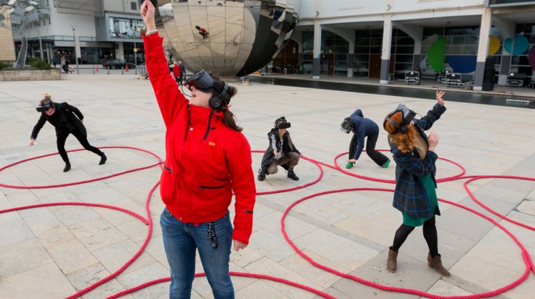 Five people dancing with VR headsets on in Millennium Square, Bristol
