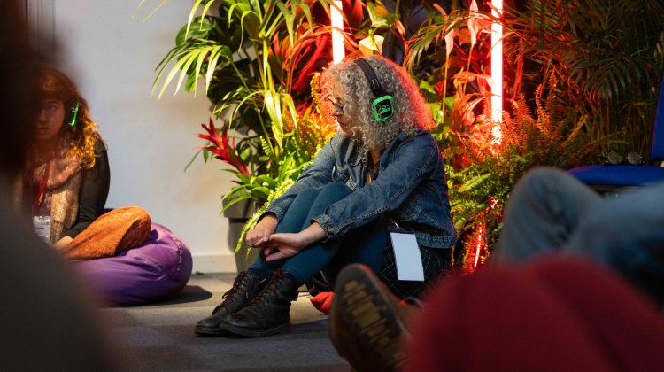 Woman sitting on floor beside some plants with headphones on