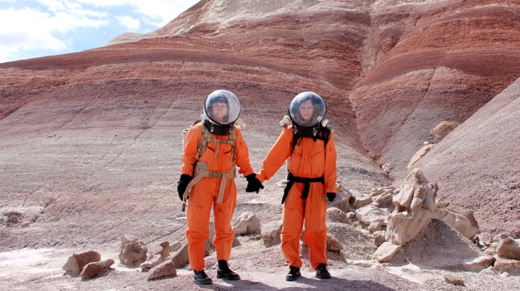 Artists Ella Good and Nikki Kent in orange space suits, from Building a Martian House
