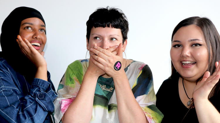 Three women with one covering her mouth with her hands