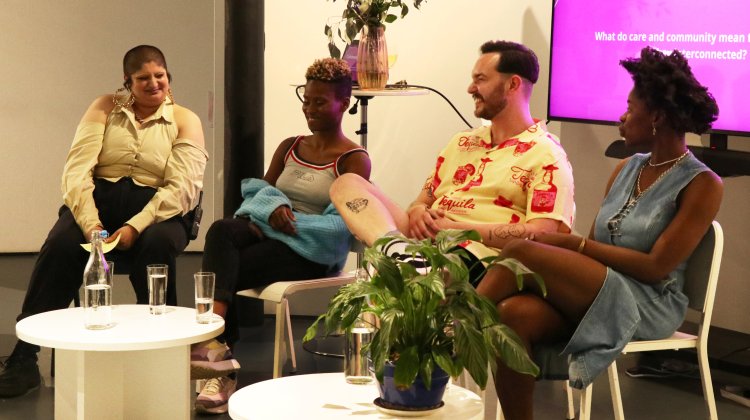 People are gathered on a stage conversing and laughing