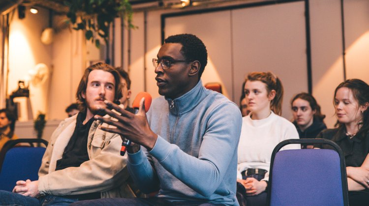 An audience member holding a microphone speaks and gestures