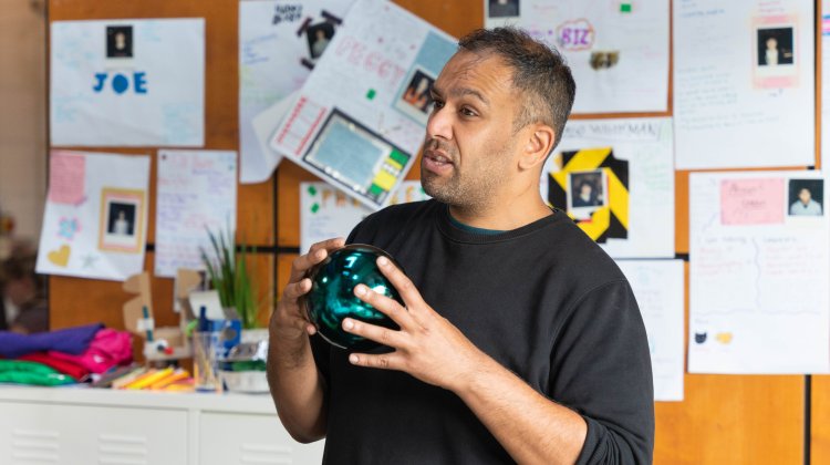 A man holding a giant bauble speaks to an audience