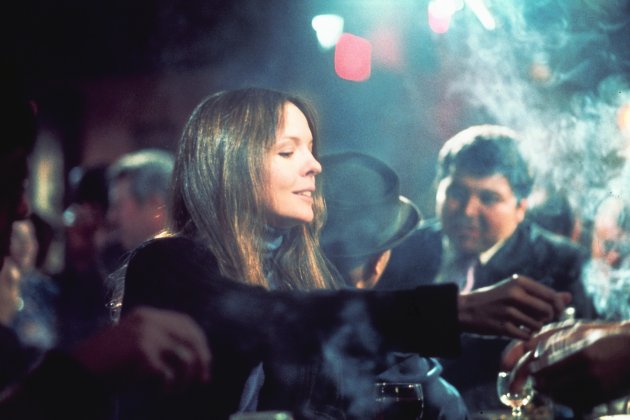 A woman sits alone at a smoky bar.