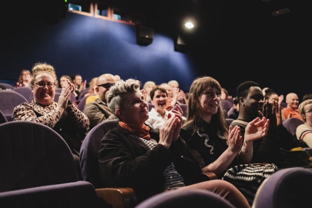 Audience members seated in a Watershed cinema clapping and smiling