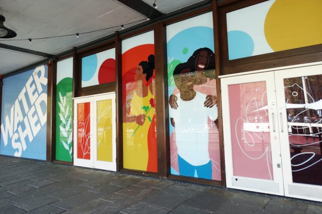 Photo of courful window illustration of people on the windows and doors of Watershed's Undershed Bar