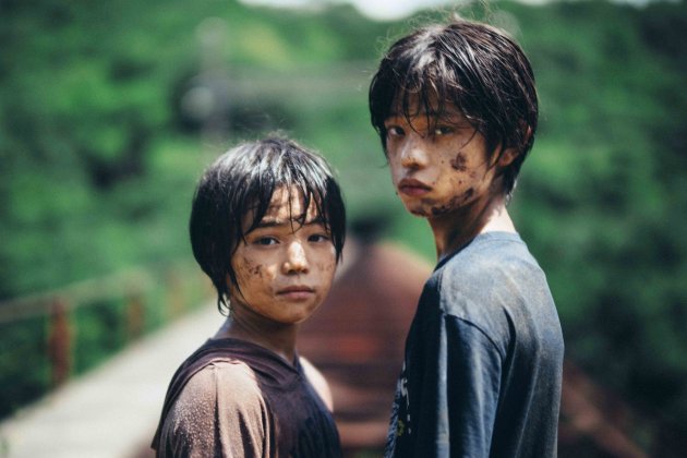 Two boys covered in mud are gazing mysteriously at the camera.
