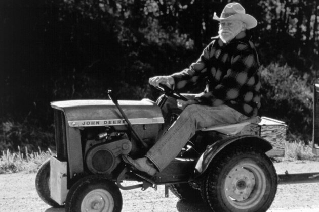 An older man sits on a John Deere tractor.